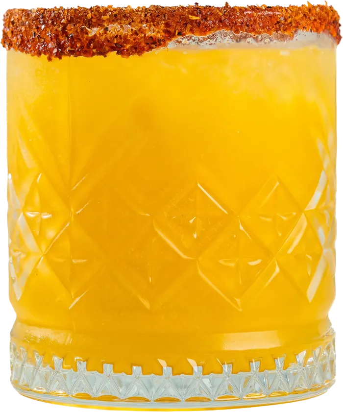 Coctel amarillo con escarchado de chile en vaso labrado.