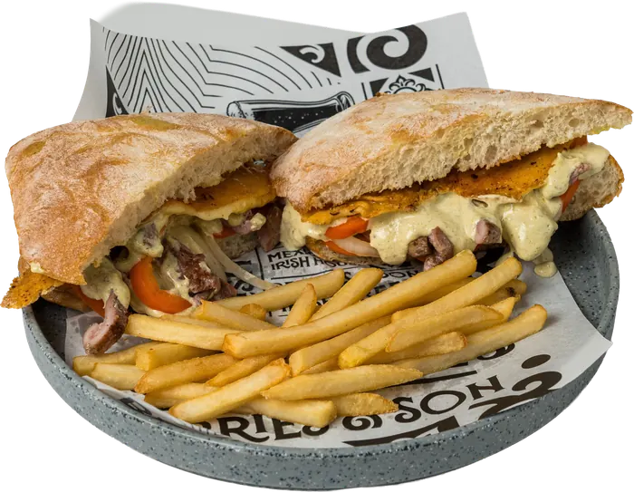 Sándwich en pan de chapata con arrachera, pimientos y queso, partido a la mitad, con papas a la francesa.